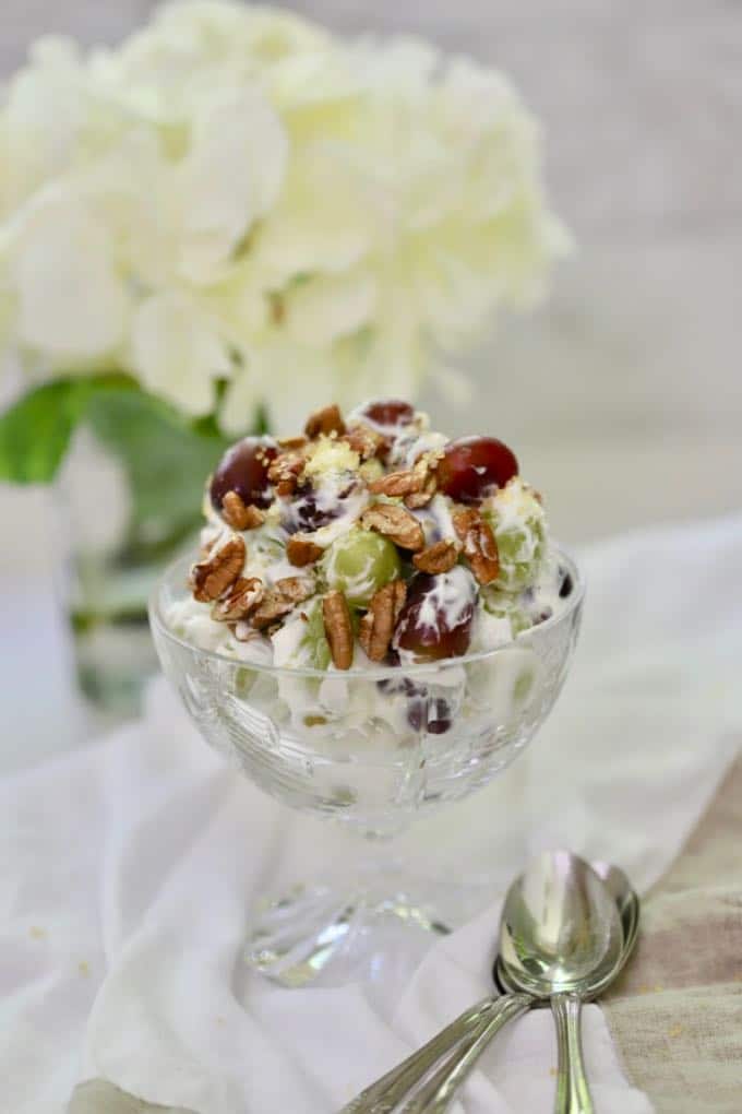Easy Grape Salad with Cream Cheese in a crystal dessert dish on a white linen napkin with spoons