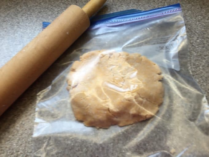 A ball of homemade Cheez-It dough in a gallon-size storage bag and rolling pin.