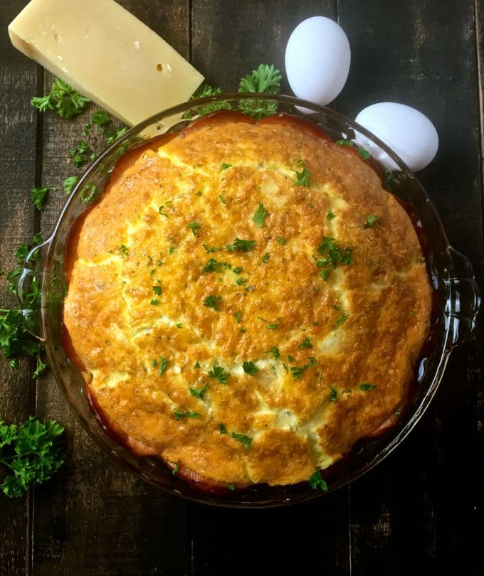 Canadian Bacon and Brie Quiche with a wedge of Parmesan cheese and two eggs.