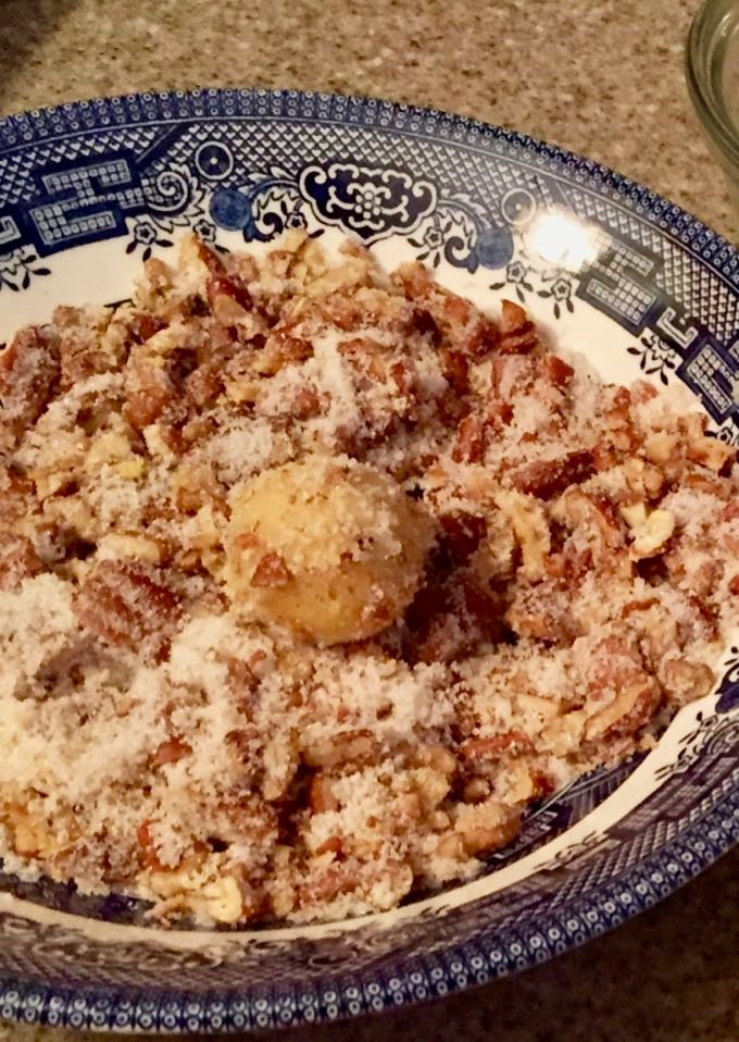 Rolling cookie dough balls in sugar and chopped pecans to make Cornmeal Cookies with Tomato Jam