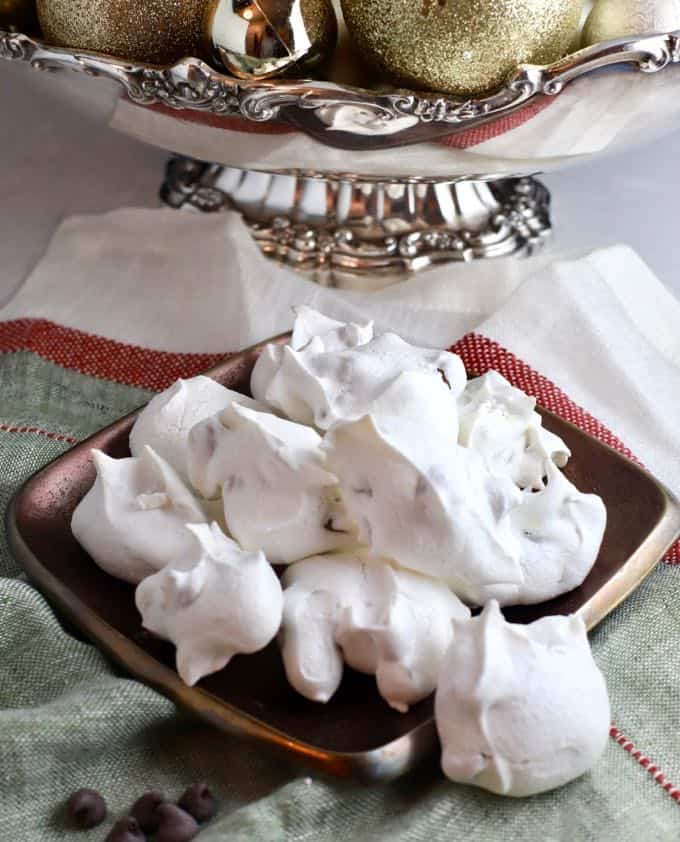 Forgotten cookies on a Christmas napkin with a bowl full of ornaments in the background.