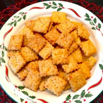 A plate of homemade cheez-it crackers on a Christmas plate.