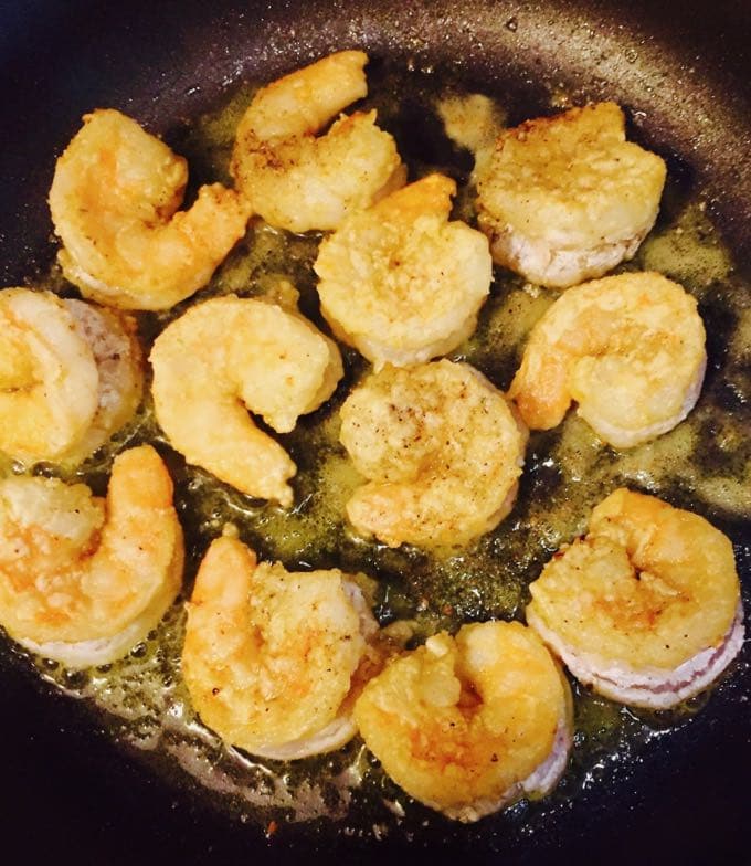 Shrimp being pan fried in a skillet. 