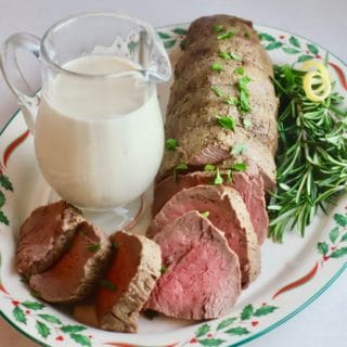 Sliced beef tenderloin on a Christmas platter garnished with parsley.