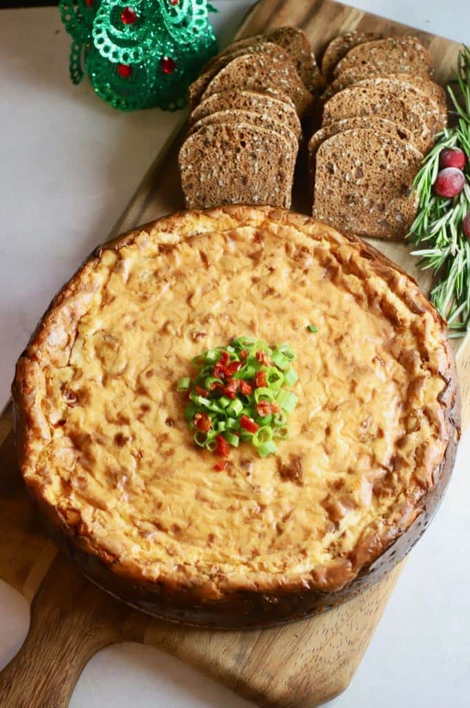 Savory Havarti and Sun-Dried Cheesecake on a wooden cutting board with crackers