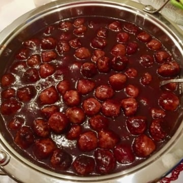 Glazed turkey meatballs with grape jelly and chili sauce in a chafing dish.