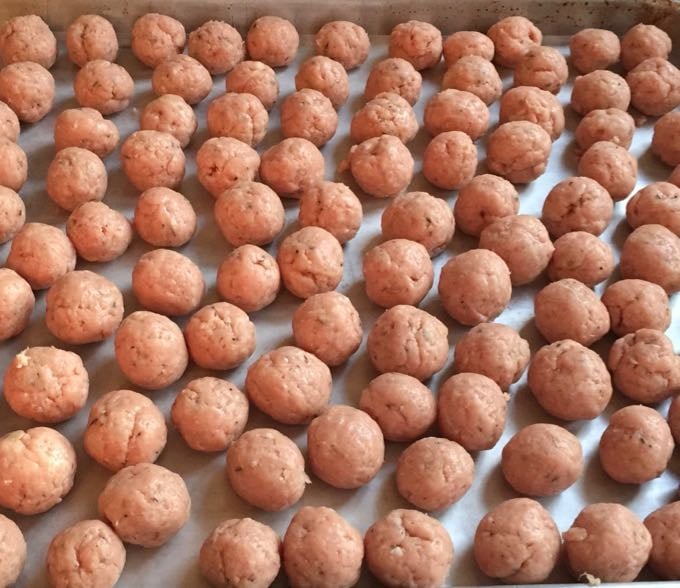 Turkey meatballs spread out on a baking sheet.