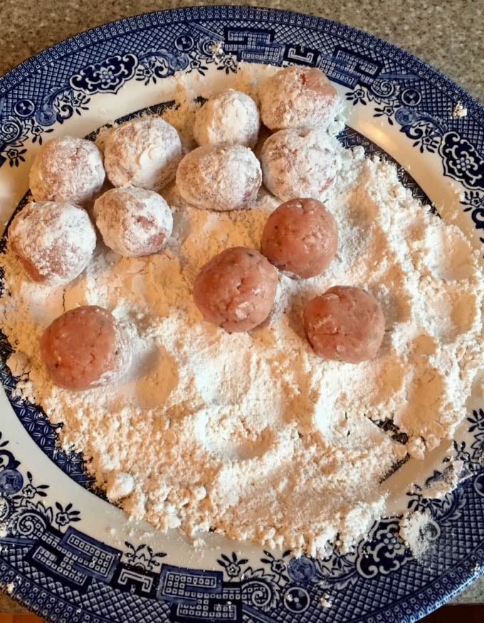 Coating turkey meatballs with flour before frying.