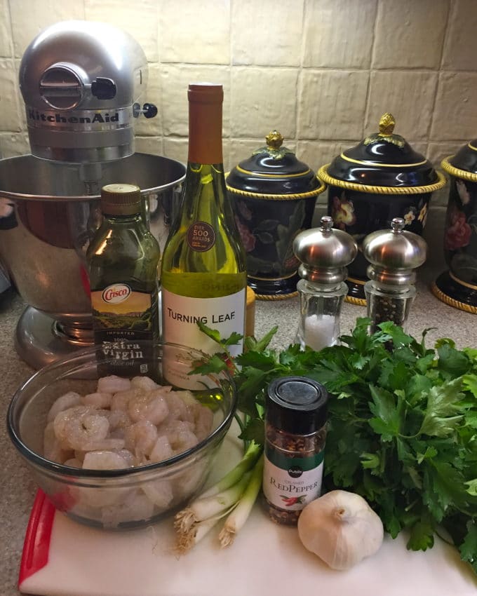 A bottle of wine, olive oil, scallions, shrimp, red pepper flakes, parsley and garlic, ingredients for Spicy Shrimp and Green Sauce