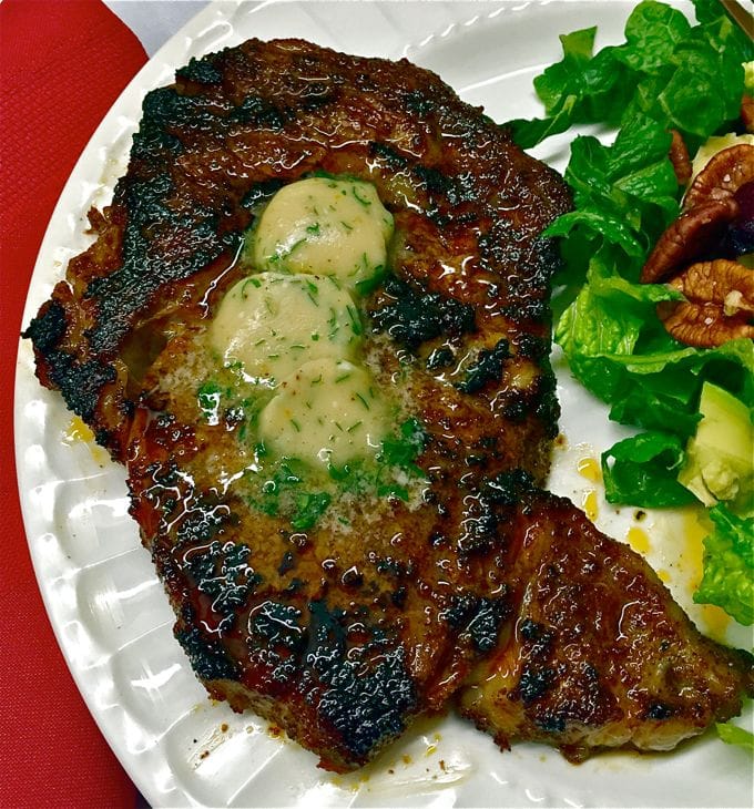 Chili Rubbed Ribeye Steak with Maple Bourbon Butter on a plate with salad