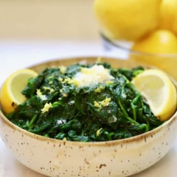 Sauteed Spinach with Lemon and Garlic in a bowl with a pat of melted butter on top.