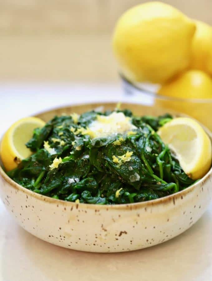 Sauteed Spinach with Lemon and Garlic in a bowl with a pat of melted butter on top.