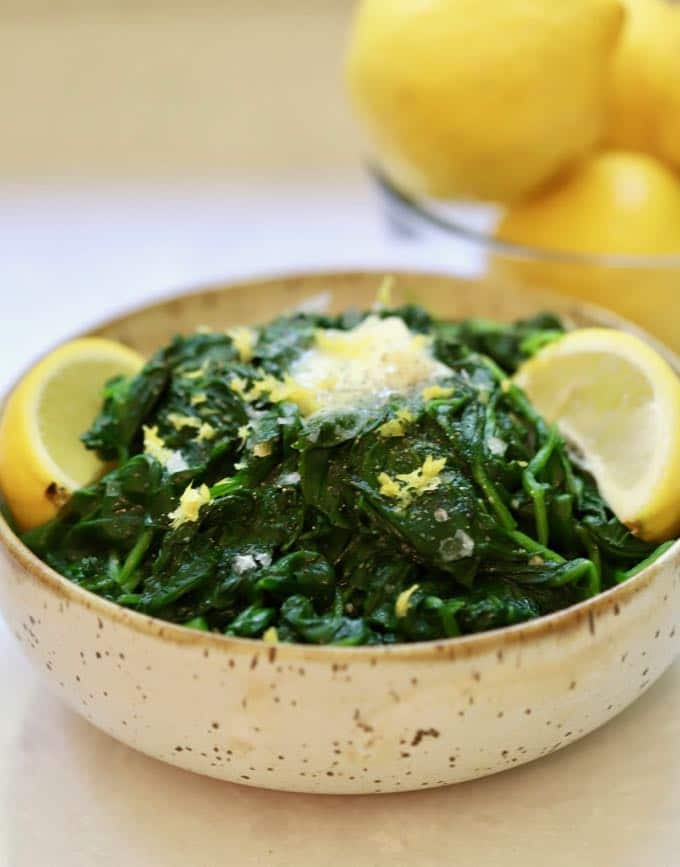 Sautéed Spinach with Lemon and Garlic garnished with lemons and butter