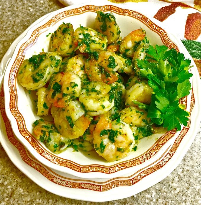 Shrimp with a green sauce made with parsley and scallions in a bowl and garnished with parsley
