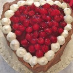 Chocolate Cherry Valentine Torte baked in the shape of a heart with cherries in the middle on a plate.