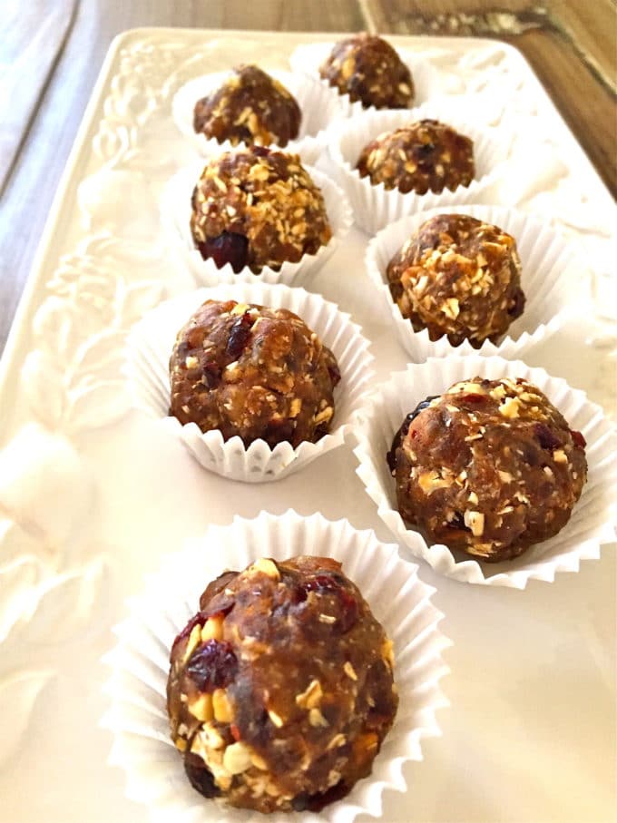 Healthy No Bake Oatmeal Balls in paper holders on a white plate.