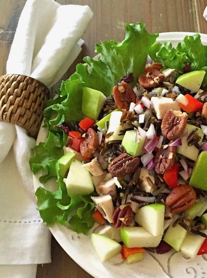 Healthy Wild Rice Chicken Salad on a bed of lettuce in a white serving bowl