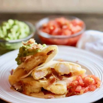 Shrimp and Bacon Quesadillas on a plate with avocado and salsa toppings