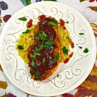 Loquat and Cranberry Chicken on a bed of orzo on a white plate.