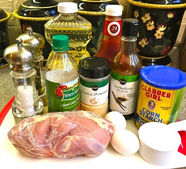 Chicken parts in a bag, plus vinegar, garlic powder, soy sauce, cornstarch and cooking oil on a cutting board. 