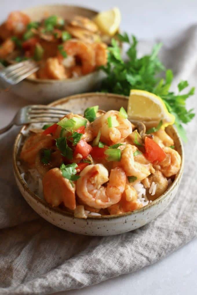 Shrimp Creole in two bowls garnished with lemon wedges and parsley.