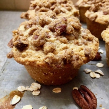 An oatmeal muffin with an oatmeal crumble topping on a baking sheet.