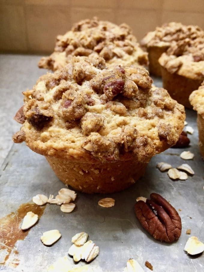An oatmeal muffin with an oatmeal crumble topping on a baking sheet.