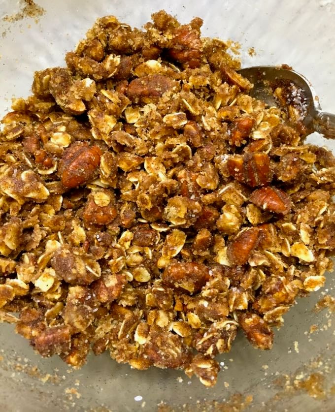 Oatmeal muffin topping of oats, butter, nuts, and brown sugar in a bowl.