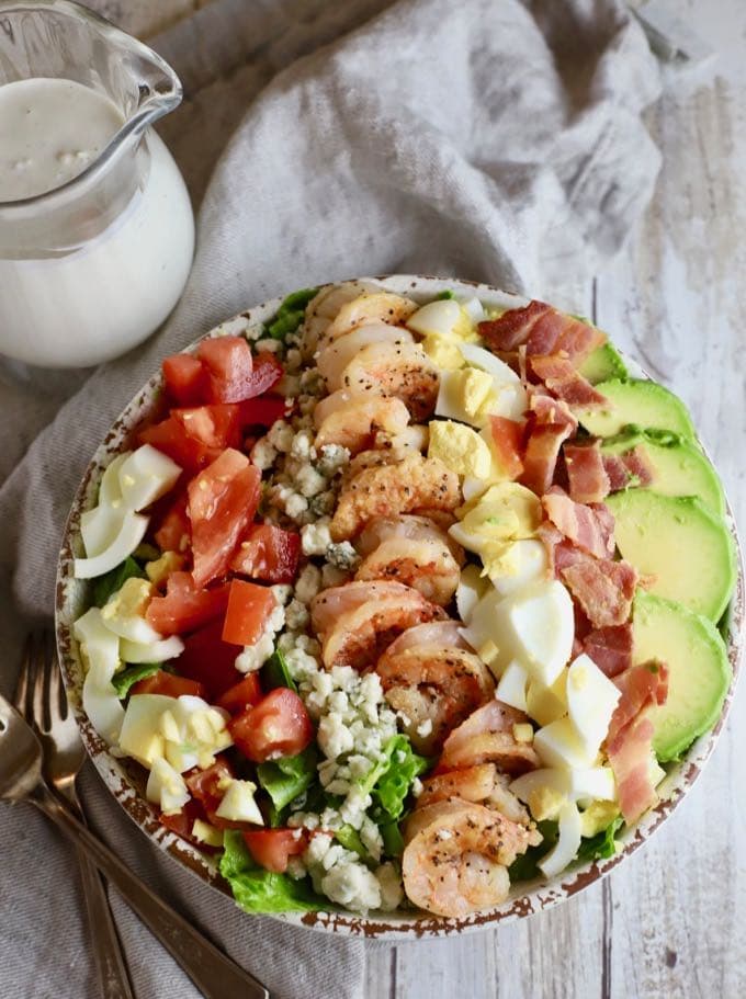 Shrimp Cobb Salad in a bowl with eggs, tomatoes, shrimp, avocado, and bacon.