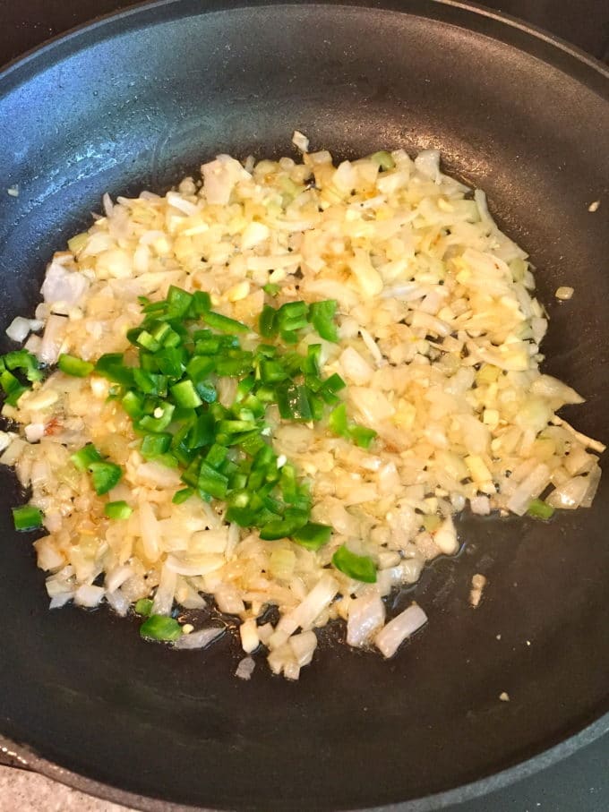 Onions and jalapeños cooking in a skillet. 