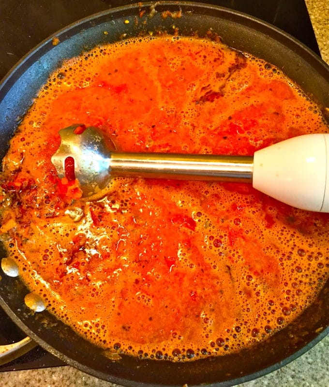 Using an immersion blender to puree soup in a skillet. 