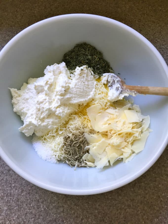 Mixing ricotta, parmesan and mozzarella cheeses and seasonings in a bowl for Easy Make Ahead Baked Ziti