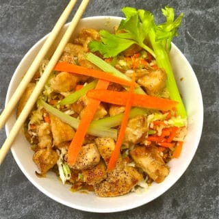 Chicken egg roll bowl garnished with celery and carrots and a pair of chop sticks.