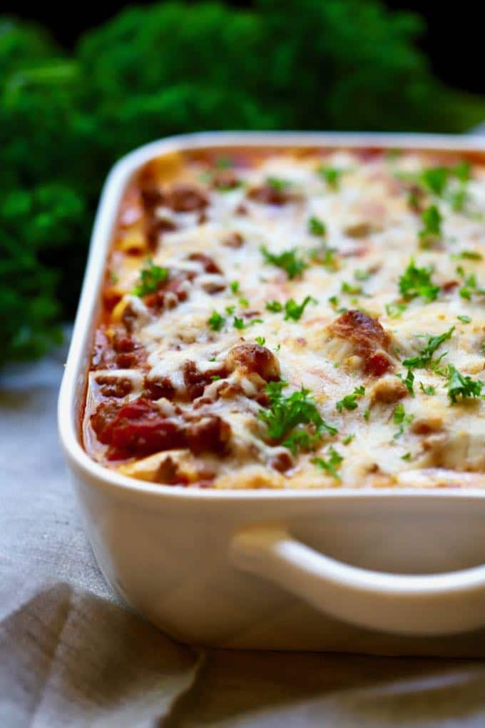 Easy Make Ahead Baked Ziti in a white baking dish garnished with fresh parsley