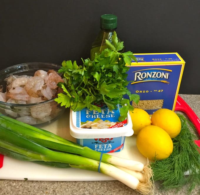 Ingredients for a shrimp pasta salad including orzo, lemons, dill, shrimp and feta cheese.