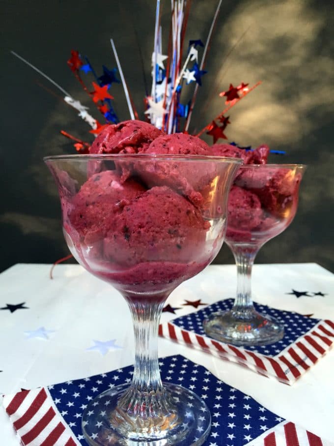 Several scoops of mixed berry sherbet in a clear glass dessert dish.