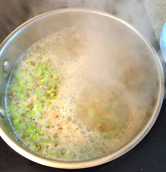 Peas cooking in a saucepan on the stove.