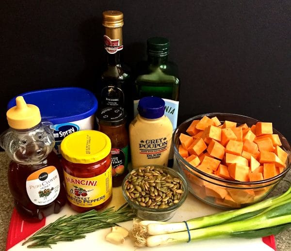  Roasted Sweet Potato Salad ingredients on a cutting board including cubed sweet potatoes and toasted pumpkin seeds.