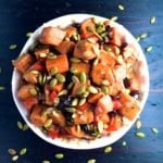 Roasted Sweet Potato Salad topped with toasted pumpkin seeds in a white bowl.