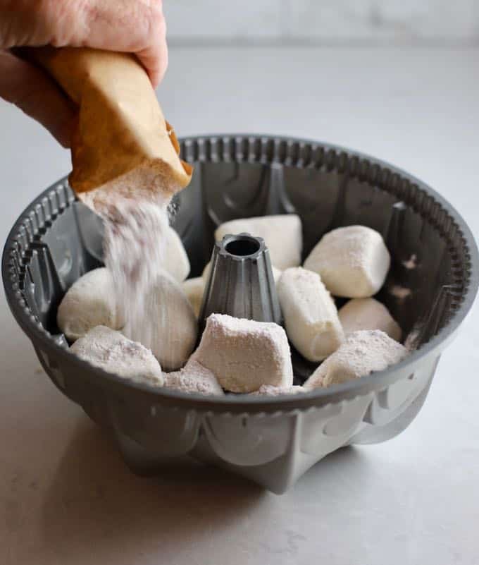 Sprinkling dry butterscotch pudding mix over frozen dough rolls in a bundt pan.