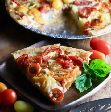 Southern Style Cherry Tomato Pie garnished with basil and cherry tomatoes in a white bowl on the side.