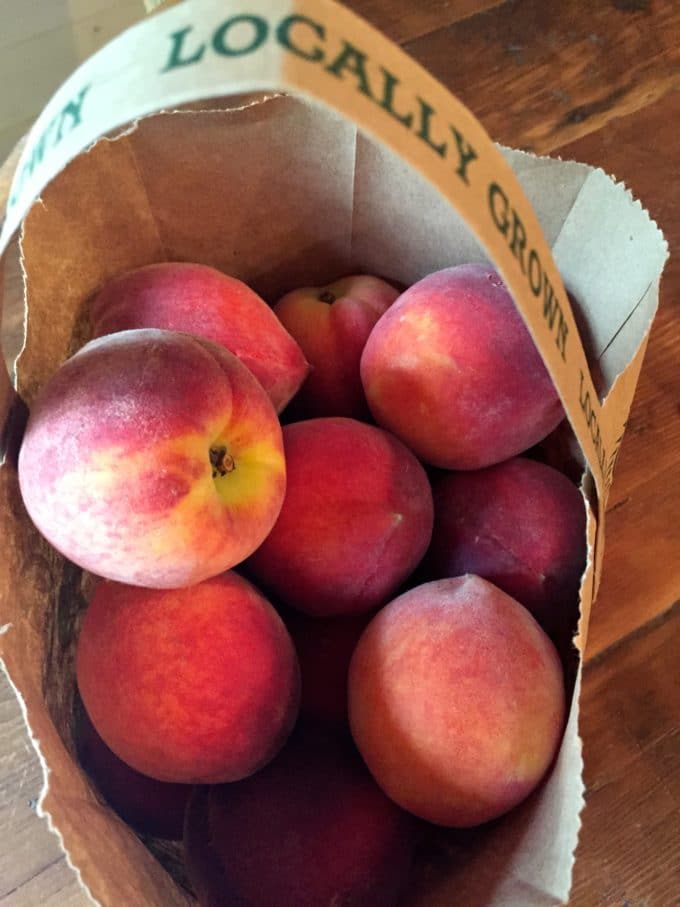 A paper bag full of whole peaches.
