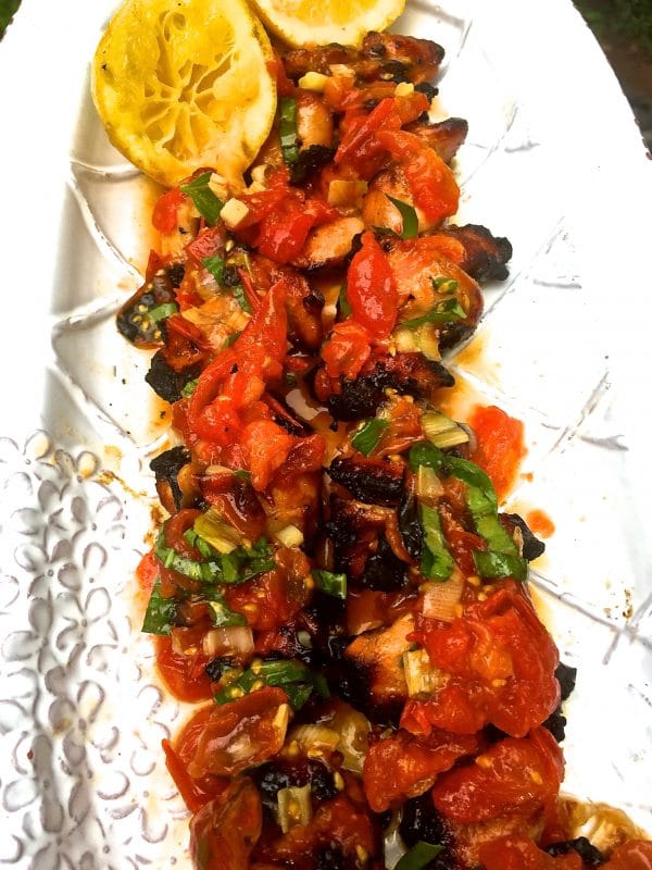 Grilled Chicken Skewers with Tomato Relish on a serving platter garnished with scallions and lemon.