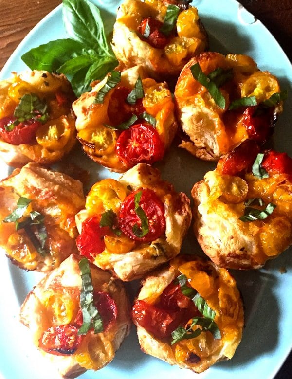 Muffin Pan Tomato Tarts with Puff Pastry on a plate garnished with basil.