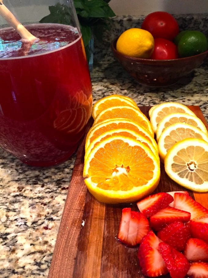 Slices of oranges and lemons ready to be added to a glass pitcher of Summer Rose Sangria