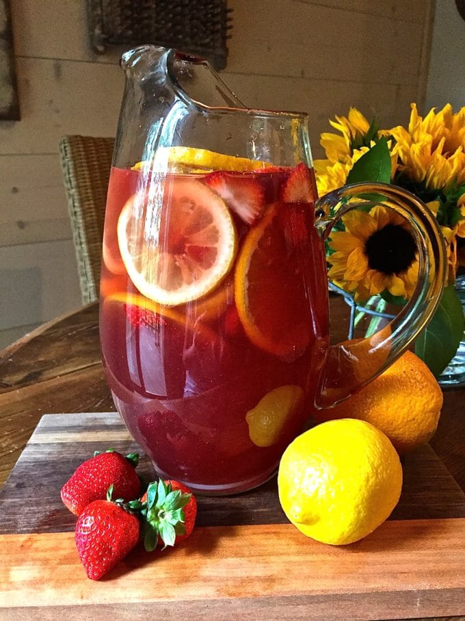 Sangria in a glass pitcher with orange and lemon slices and strawberries