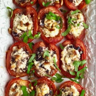 Roasted Tomatoes with Feta, Olives and Pine Nuts garnished with chopped basil on a serving plate.