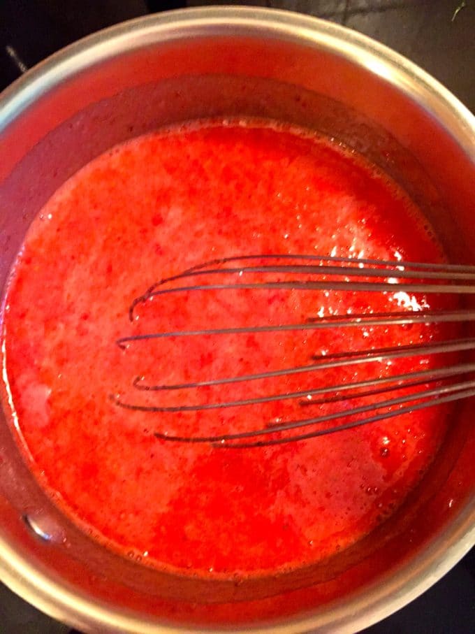 Strawberry puree in a pan with a whisk.