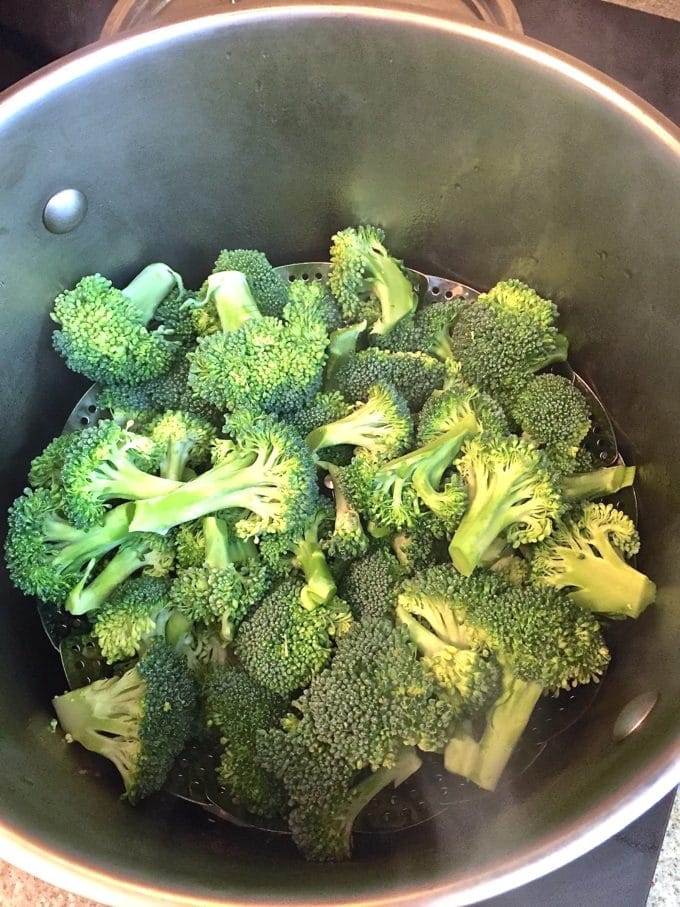 A saucepan filled with broccoli florets to steam for Potato Broccoli Salad with Vinaigrette