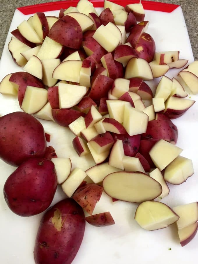 Cut up new potatoes on a cutting board for Potato Broccoli Salad with Vinaigrette